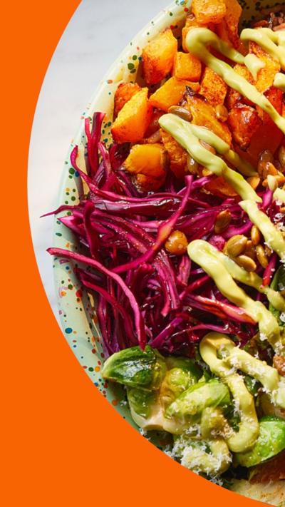 A bowl filled with roast pumpkin, crispy chickpeas, charred sprouts, zesty red cabbage and a creamy avocado sauce.