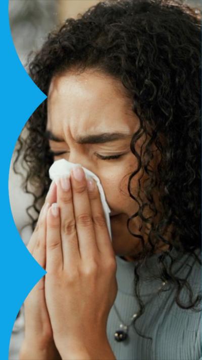 Woman sneezes into a tissue