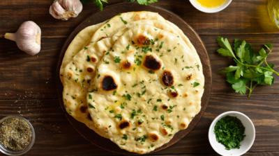 Top view of garlic butter naan and some of the ingredients laid out on a wooden table