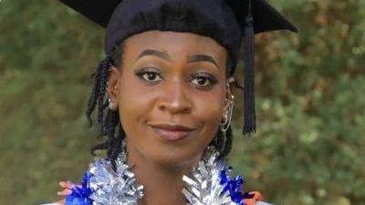 A photo of the late Desree Moraa Obwogi looking at the camera while wearing a university graduation hat against a green background that looks like possibly foliage.