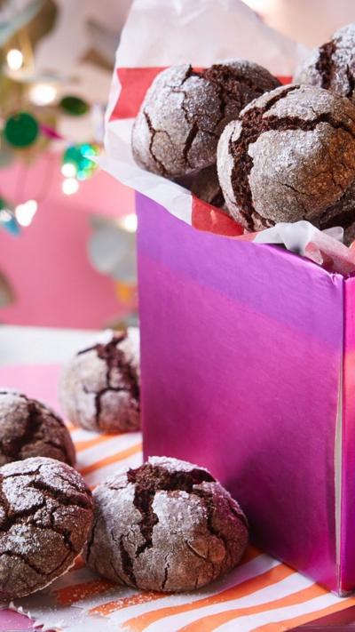 Christmas crinkle cookies are arranged in a pink box and beside it 