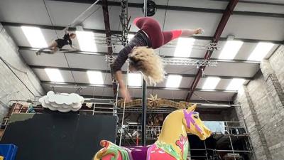 A woman doing acrobatics above a toy horse