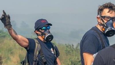 A firefighter with a mask stands in the middle of moorlands