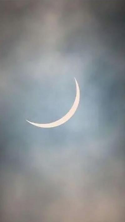 A crescent sun behind clouds