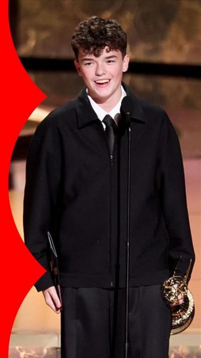 Owen standing on the stage accepting his award while smiling