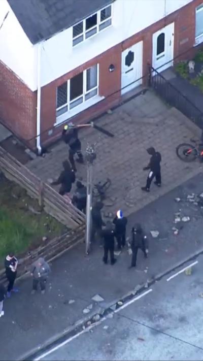 Protesters breaking the front of a property to take bricks