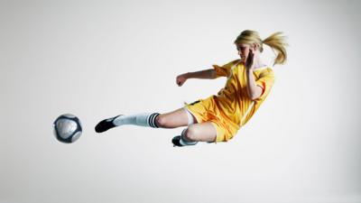 Image of a footballer kicking a ball while leaping in the air 
