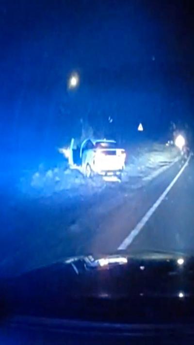 A car crashed and the blue lights of a police car glow in the dark night