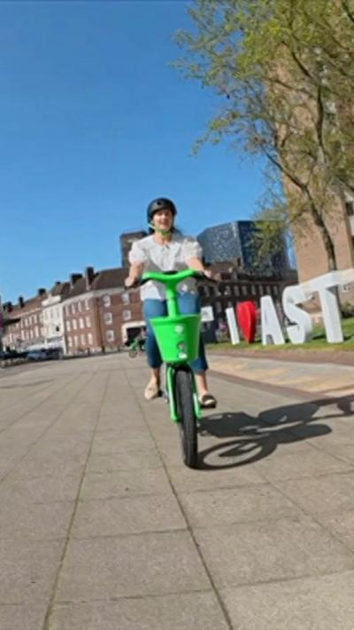 Woman wearing white top and jeans riding a green and white bike