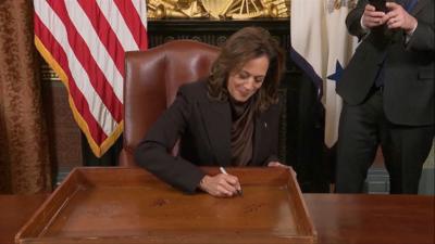 Harris signing her desk and smiling