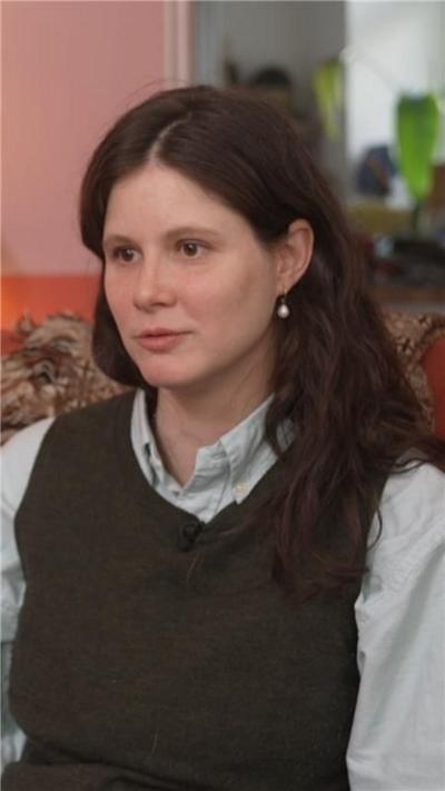 Woman sitting in a room wearing shirt.