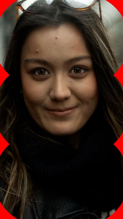 A woman with long dark hair looks straight to the camera.