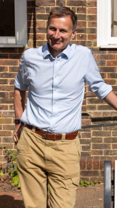 A man, Jeremy Hunt, stands in a light coloured shirt and trousers