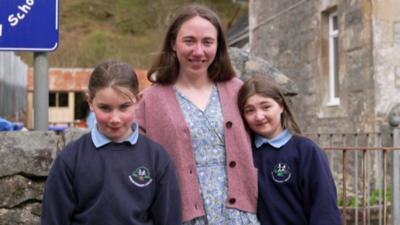 two girls standing next to teacher. 