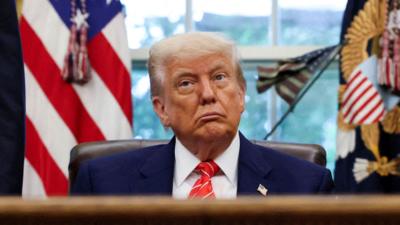 Donald Trump sits in the Oval Office