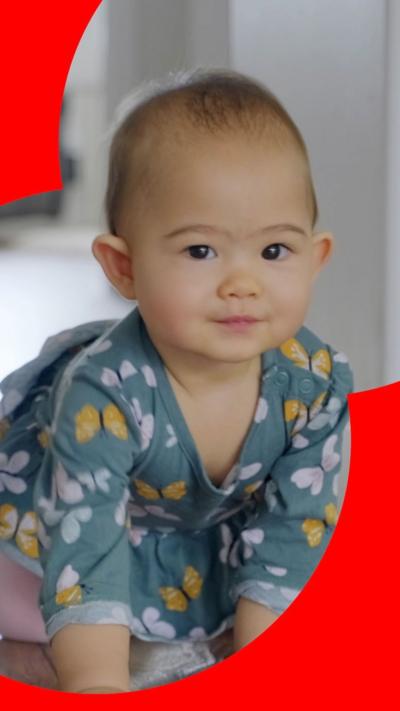 A baby crawls on the ground and looks at the camera