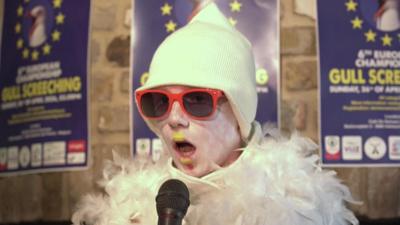 a child dressed as a seagull with sunglasses and a microphone.