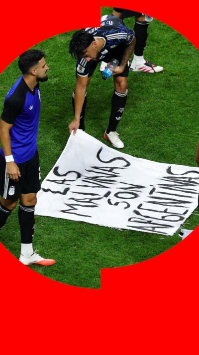 Argentina players look at a banner on the pitch which says 'Las Malvinas son Argentinas'