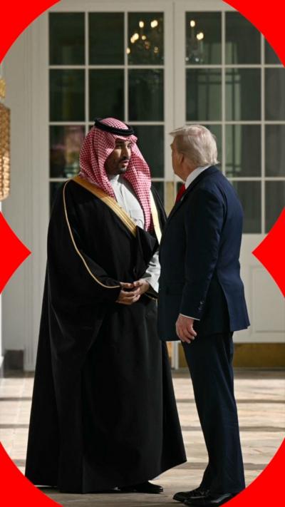 A man in traditional Saudi dress shakes hands with a man in a blue suit. 
