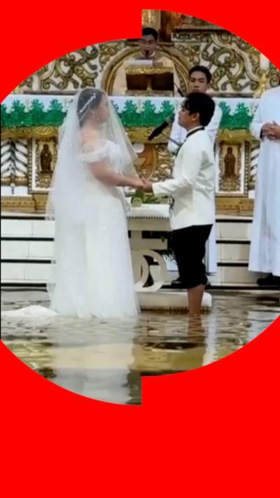 A couple in a church holding hands, wearing wedding outfits, standing in water