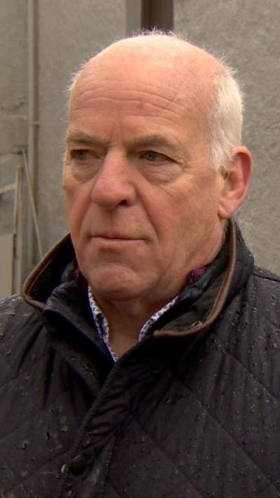A man with thinning white hair in a navy padded jacket 
