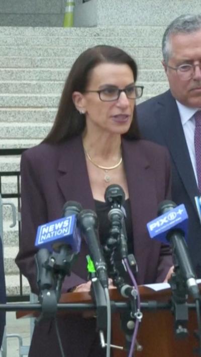A woman speaks into microphones.