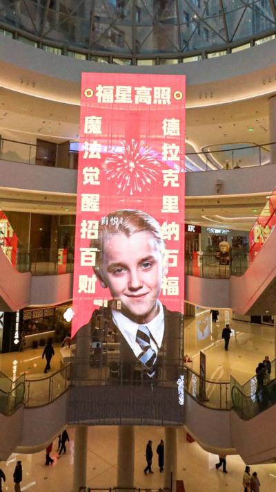 Large puster of Draco Malfoy hangs from a shopping mall ceiling
