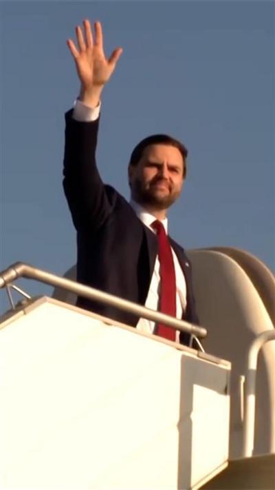 JD Vance waves before boarding a plane.