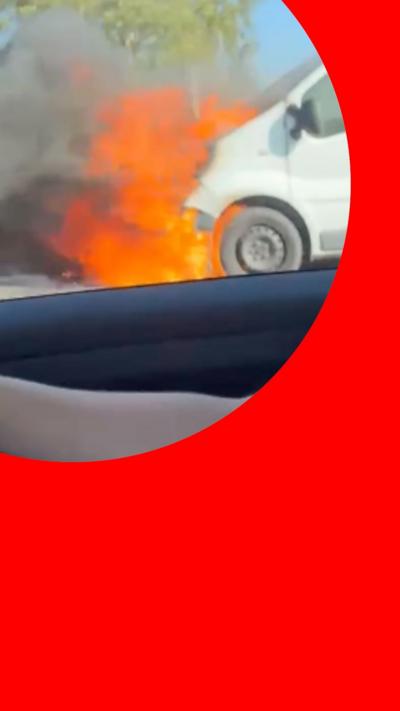 White van on fire at the side of the road