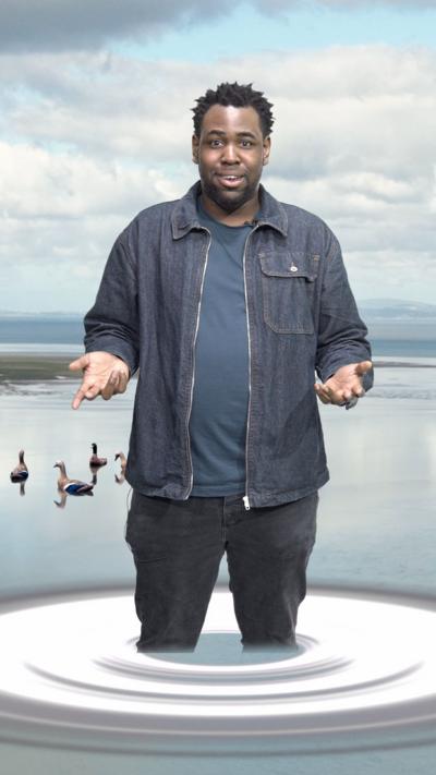 A man is edited to look like he is stood in the water, with an edited ripple. There are also four edited ducks in the water. The background is a green screen of water and blue skies with white fluffy clouds.