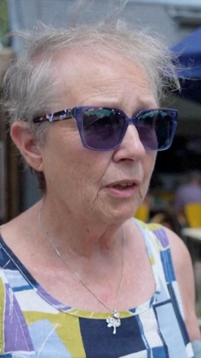 A woman wears dark purple glasses and a dress