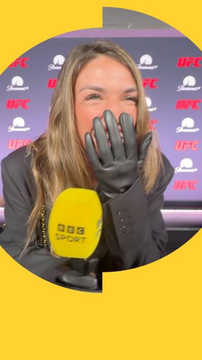UFC strawweight champion Mackenzie Dern covers her mouth with her hand while holding a BBC Sport microphone