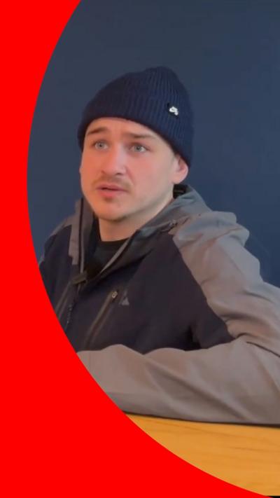 A man looking into the camera, wearing a beanie hat