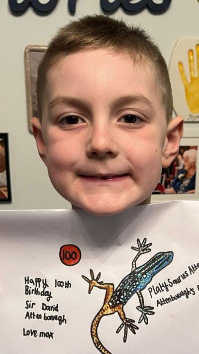 A six-year-old boy holding up a drawing of a platypus