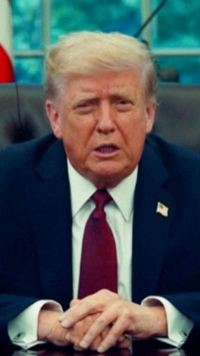 Donald Trump sat at desk in navy suit