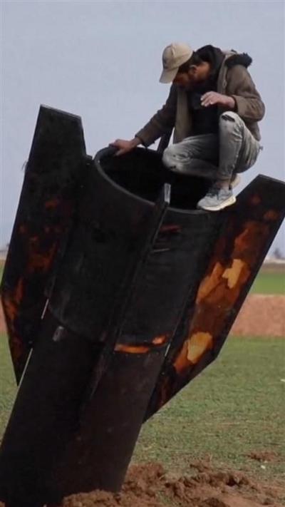 A missile sticking out of the ground with a man sat on top