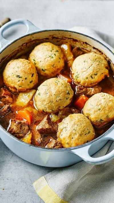 Top down view of a  blue casserole dish with stew and dumplings on top