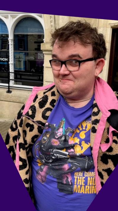 A man wearing glasses and a colourful jacket with a leopard print looks unsure.