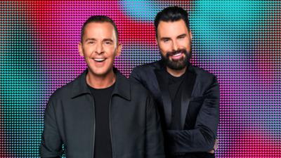 Scott Mills and Rylan Clark smile while posing for the camera.