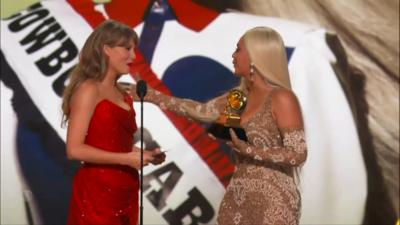 Beyoncé embraces Taylor Swift while holding her Grammy award on stage