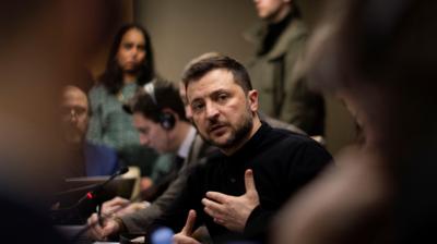 President Zelensky, wearing a black top, surrounded by reporters