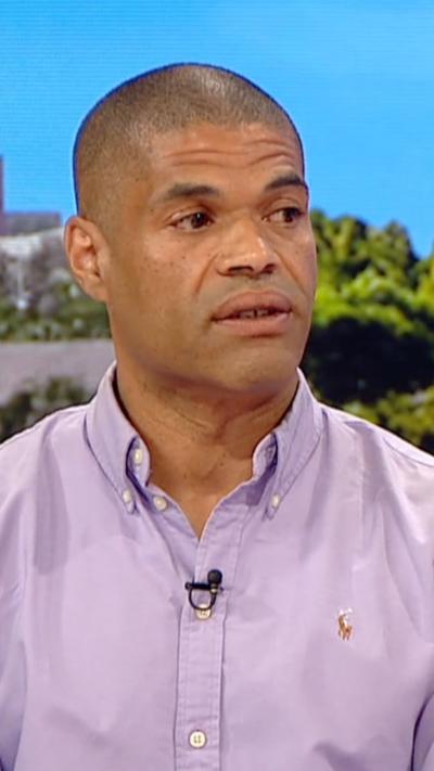 Man wearing lilac shirt sat on BBC Breakfast sofa