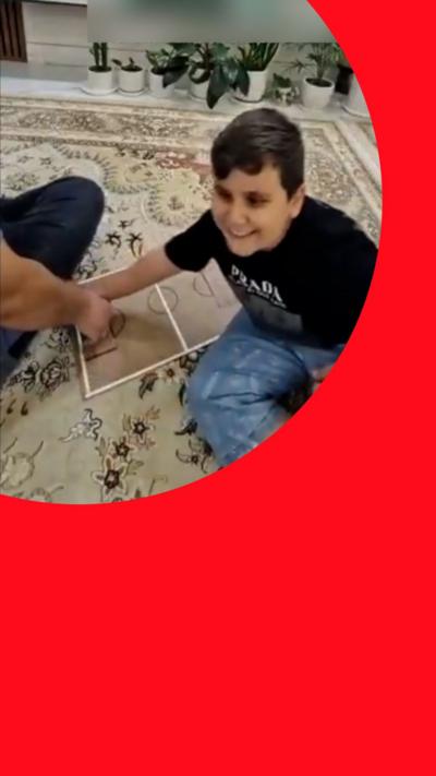 Boy smiling on carpet with a football tactics board in front of the football on TV