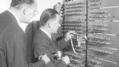 Men working on an old fashioned computer