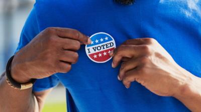 A man puts a sticker on his shirt that says 'I voted'