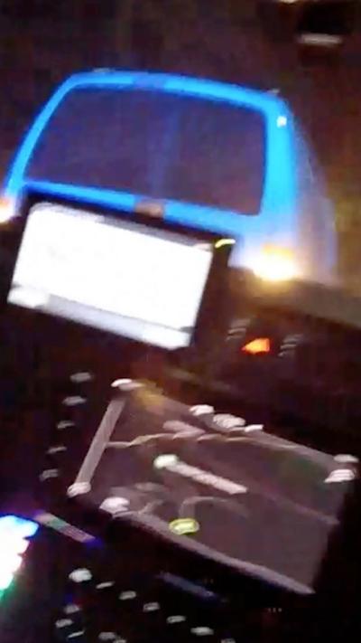View from a police car front windscreen showing a lit up display and a vehicle with reversing lights on about to ram into the front of the car