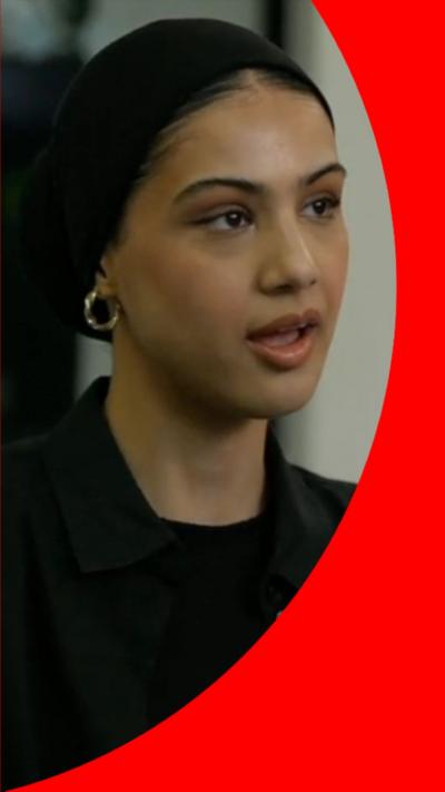 Woman with tied-back dark hair, wearing a black jacket looks side-on to the camera.