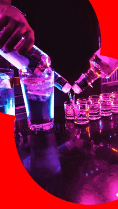 A bartender pours a row of shots from two bottles at the same time.