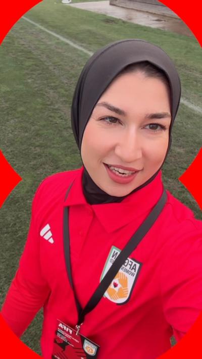 Woman in red football jersey at pitch