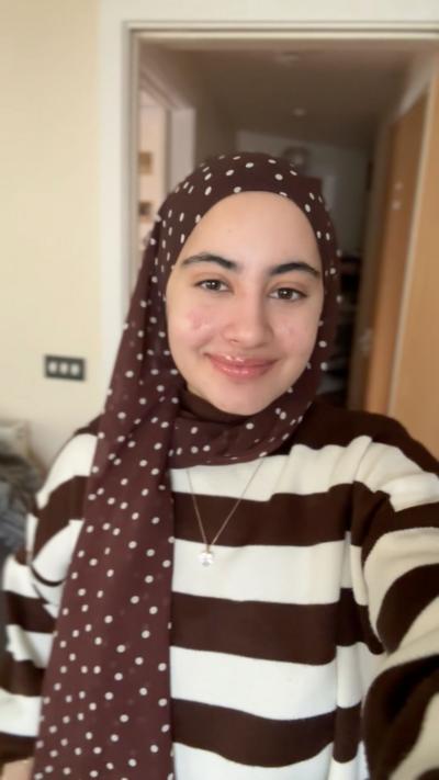 Anaba Khan, who is wearing a brown headscarf with white dots, smiling 